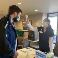 A nurse checking an individuals temperature with a handheld infrared thermometer at the COVID screening station at a St. Luke's entrance. .
