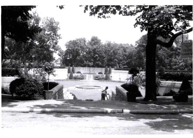 Black and white photo of worker sweeping stairs leading to Chapel Gardens.