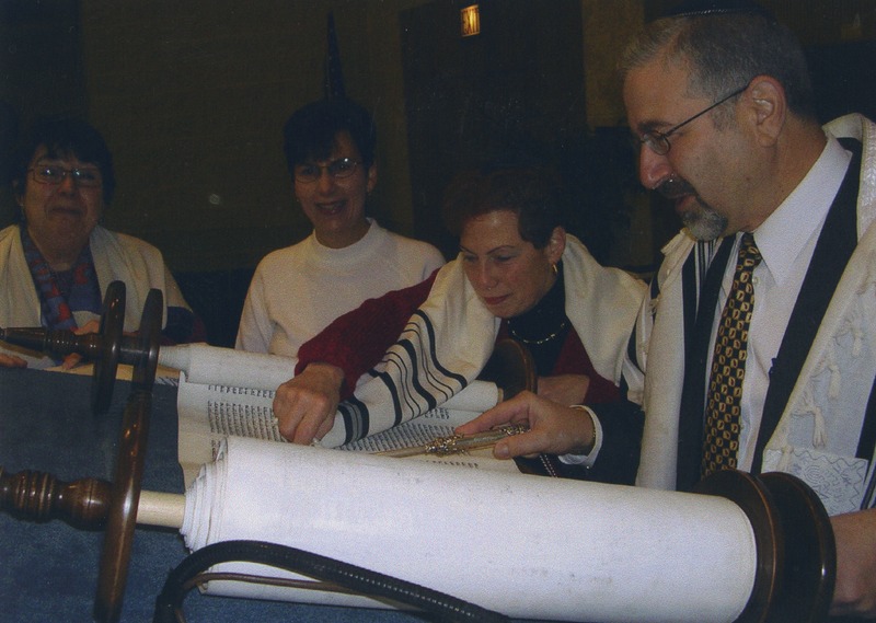 Photograph of four congregation members looking over the Torah the congregation had commissioned.