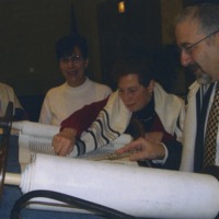 Photograph of four congregation members looking over the Torah the congregation had commissioned.